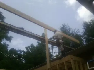 Carpenter setting a ridge beam over a new addition frame — Ice Dam Removal by Roofing Brothers in Baker
