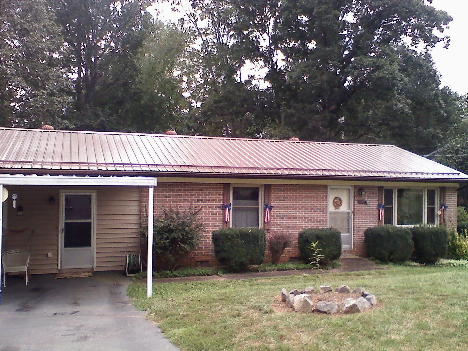 Bronze metal roof and carport on a brick ranch home — Roof Repair work by our crew in Baker